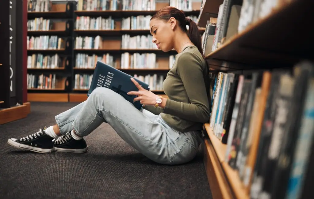 Book, reading and library student on floor with learning, education and research for school, univer
