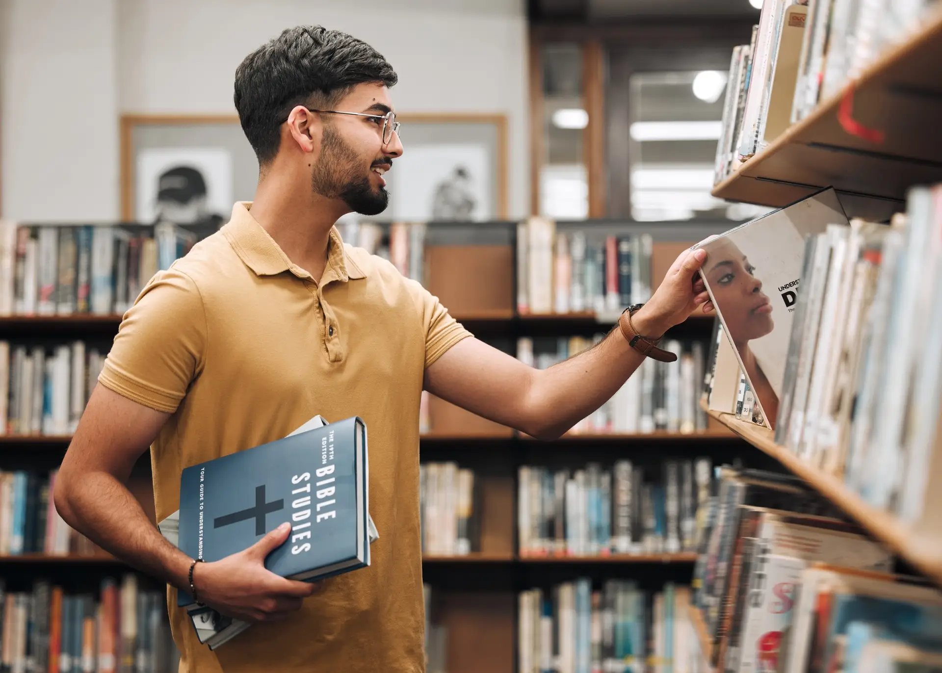 University, student or man with bible in a library to study spiritual religion knowledge, prayer or